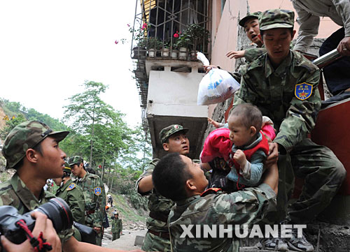 5月13日，在震后的北川縣城，武警戰(zhàn)士將一名和家人失散的幼童救出。 記者從四川省綿陽(yáng)市抗震救災(zāi)指揮部了解到，受災(zāi)特別嚴(yán)重的北川縣老縣城80%、新縣城60%以上的建筑物因地震垮塌，縣城周邊發(fā)生大面積山體滑坡。