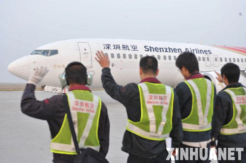 12月15日，工作人員在深圳機場向即將起飛的飛機揮手致意。 當日早上7時20分，作為兩岸直接“三通”首個飛往臺灣的大陸航班，深圳航空ＺＨ９０９５航班正式從深圳機場起飛。 新華社記者壯錦攝