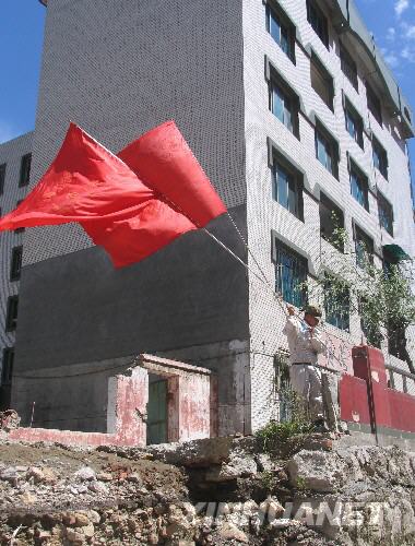  7月5日，一名防化兵高舉紅旗在北川縣城內(nèi)行走。當(dāng)日，記者經(jīng)特許進(jìn)入地震重災(zāi)區(qū)北川縣城采訪，用相機(jī)記錄下北川縣城的現(xiàn)狀。 